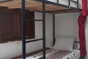 Una cama litera con cabecera de madera y una ventana con persiana de madera.