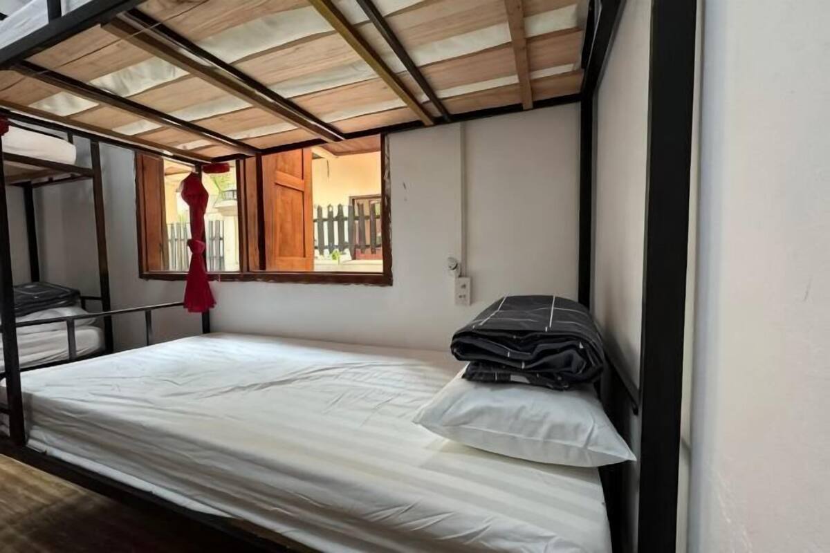 A bunk bed with a mattress, pillows, and a red object hanging from the ceiling.