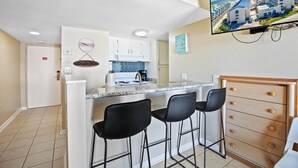 Une cuisine moderne avec des meubles blancs, un plan de travail en granit et un luminaire suspendu.