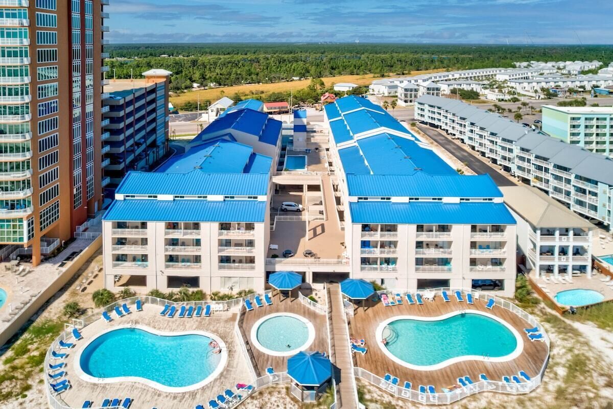 Ein Resort mit mehreren Schwimmbecken, einem zentralen Gebäude mit blauen Dächern und Blick auf die umliegende Landschaft.