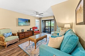 A living room with a ceiling fan, a large window, and a view of the outdoors.