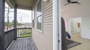 A covered porch with a view of the street, a glass door leading inside, and a ceiling fan.