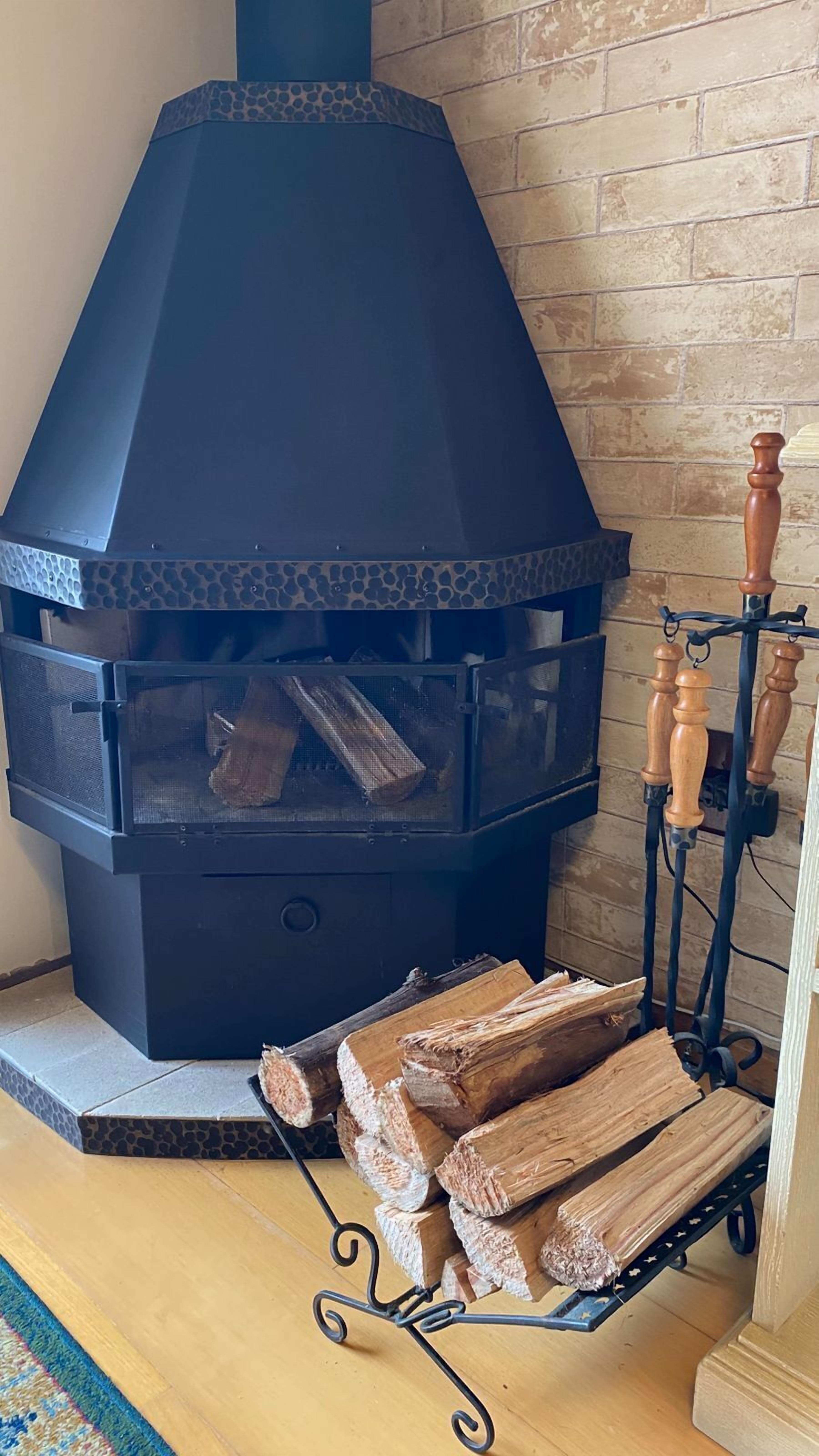 A modern fireplace with a black exterior and a clear glass front, displaying logs inside.