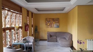 A living room with a sofa, armchairs, a glass coffee table, and a painting on the wall.