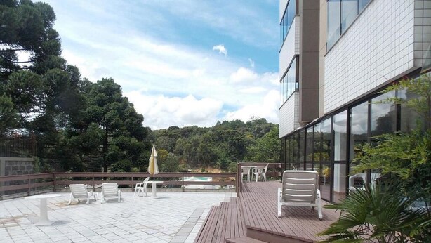 A modern building with a terrace featuring outdoor seating and a view of a forested area.