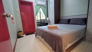 A bedroom with a bed, a desk, a chair, a red door, and a window with curtains. - Putrajaya Transit Romestay (Putrajaya)
