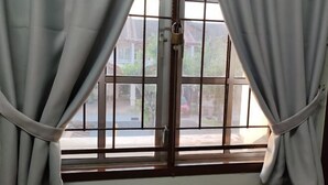 A window with metal bars and a padlock, curtains tied back, and a view of buildings outside. - Putrajaya Transit Romestay (Putrajaya)