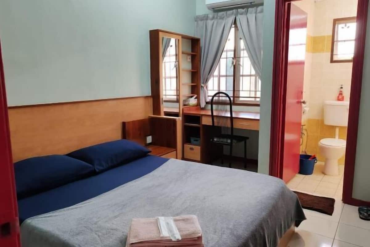 A bedroom with a bed, a desk, and a chair.