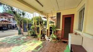 A covered porch with potted plants, a bench, and a door with a window. - Putrajaya Transit Romestay (Putrajaya)