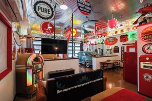 A vintage-themed room with a jukebox, a vintage car, and retro decor.