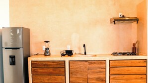 Een keuken met een roestvrijstalen koelkast, houten kastjes, een gasfornuis en een koffiezetapparaat.