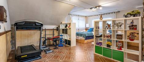 Une pièce comprenant un espace dédié à la musculation, un lit et une bibliothèque.