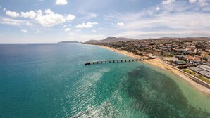 Une ville côtière dotée d’une jetée qui s’avance dans la mer, d’eaux turquoise et limpides, et d’un mélange de bâtiments résidentiels et commerciaux.