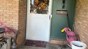 Een voordeur met een krans, een flamingo-versiering en een brievenbus.