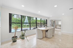 A spacious room with a large window, a round table, and a potted plant.