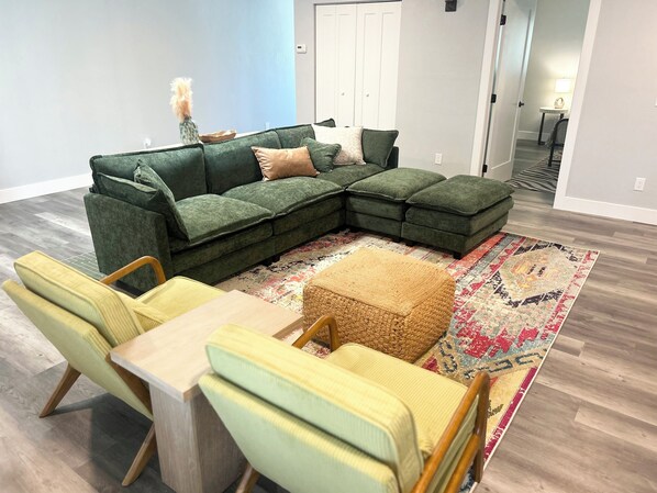 A modern living room with a sectional sofa, a small table, and matching chairs. - Spacious 4-Bed Retreat with Pool Short Stroll to the Beach (Fort Myers Beach)
