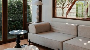 A modern living room with a beige sofa, a round table with a white object, and a lamp. - Sense of Jedyod - near Maya Nimman (Chiang Mai)