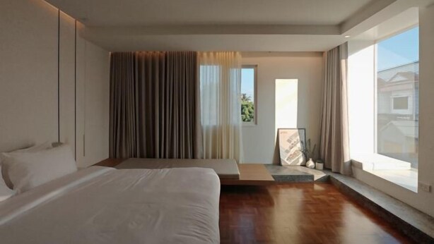 A modern hotel room with a large bed, a seating area, and a view of the outdoors. - Sense of Jedyod - near Maya Nimman (Chiang Mai)
