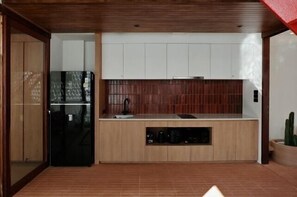 Uma cozinha moderna com armários de madeira, uma geladeira preta e um forno embutido.