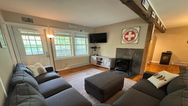 Ein Wohnzimmer mit Kamin, Wandfernseher und einer Sofagarnitur.