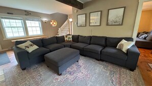 Ein Wohnzimmer mit einer Eckcouch, einem gemusterten Teppich und einer Treppe, die zu einer anderen Ebene führt.