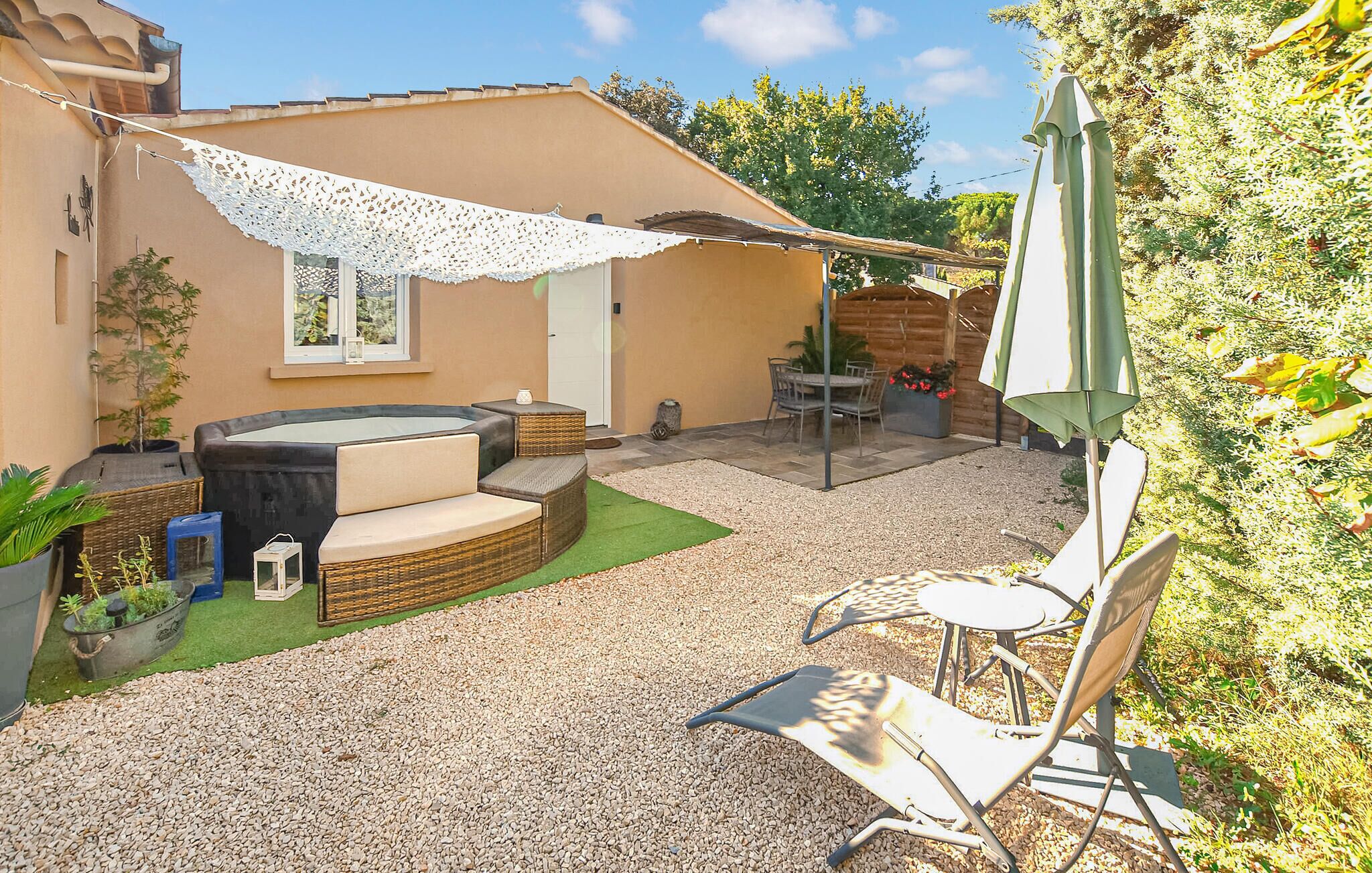 Un patio con hidromasaje, mobiliario de exterior y una mesa con sillas.