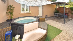 Ein Whirlpool mit Korbsitz, einem kleinen Tisch und Stühlen in einem Garten mit Pergola.