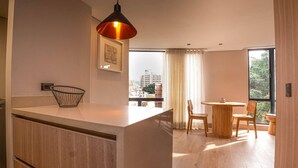 A modern kitchen with a wooden island, pendant lighting, and a view of the city through large windows. - Laureles Second Park 2BR-2AC Apt with fast WiFi (Medellín)