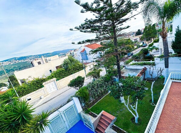 A residential area with houses, a blue gate, and a view of the sea.
