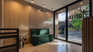 Un interior moderno con un banco tapizado en verde, una pared de listones de madera y un ventanal que da al exterior.