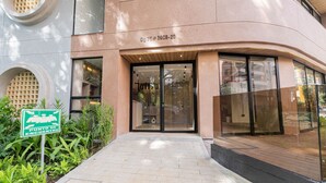 Un edificio moderno con fachada curva, entrada de vidrio y un cartel que indica un punto de encuentro.