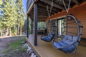 Een houten terras met twee rotan hangstoelen.