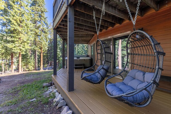 A wooden deck with two wicker swing chairs.