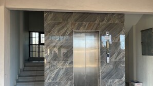 Un ascensor moderno con paredes de mármol, una escalera y una puerta de metal.