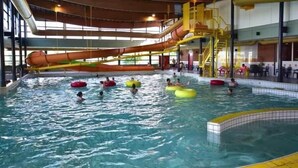 Una piscina interior con varias pistas, un tobogán acuático y flotadores inflables.