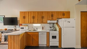 Een moderne keuken met houten kastjes, een magnetron, een spoelbak, een fornuis en een koelkast.