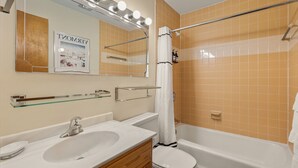 Een badkamer met een wastafel, spiegel en bad.