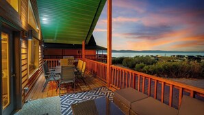 A wooden deck with a view of the ocean at sunset.