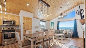 A spacious kitchen with modern appliances, a dining area with wooden furniture, and a living room with a view.