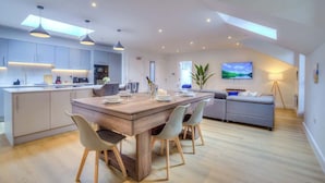 A modern kitchen with a central island, pendant lighting, and a dining area with chairs. - Penthouse Flat Manchester. 10 minutes to Airport. Sleeps 8. (Wythenshawe)
