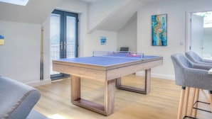 A room with a ping pong table, a sofa, and a bar area. - Penthouse Flat Manchester. 10 minutes to Airport. Sleeps 8. (Wythenshawe)