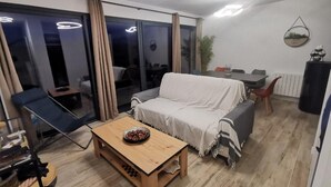 A modern living room with a sofa, a wooden coffee table, and a dining area with a table and chairs. - Chalet "L'Astragale", 6/7 pers of 60m2, 150m slopes, Risoul resort 1850 (Risoul)