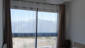A bedroom with a large bed, a view of mountains, and a ceiling light. - Chalet "L'Astragale", 6/7 pers of 60m2, 150m slopes, Risoul resort 1850 (Risoul)