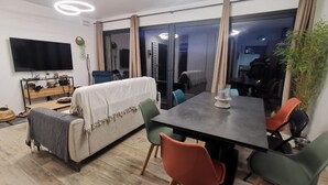 A modern living room with a sofa, a dining table, and chairs. There is a TV mounted on the wall and a plant on the table. - Chalet "L'Astragale", 6/7 pers of 60m2, 150m slopes, Risoul resort 1850 (Risoul)