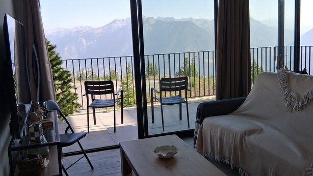 A living room with a sofa, a coffee table, and two chairs. There is a balcony with a view of mountains. - Chalet "L'Astragale", 6/7 pers of 60m2, 150m slopes, Risoul resort 1850 (Risoul)