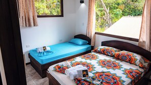 Un dormitorio con dos camas, una con cubrecama azul y la otra con un edredón estampado y colorido.