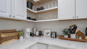 A kitchen with white cabinets, a marble countertop, a coffee maker, a toaster, and various kitchen utensils. - Family-Friendly 10 Beds Stay NOLA (New Orleans)