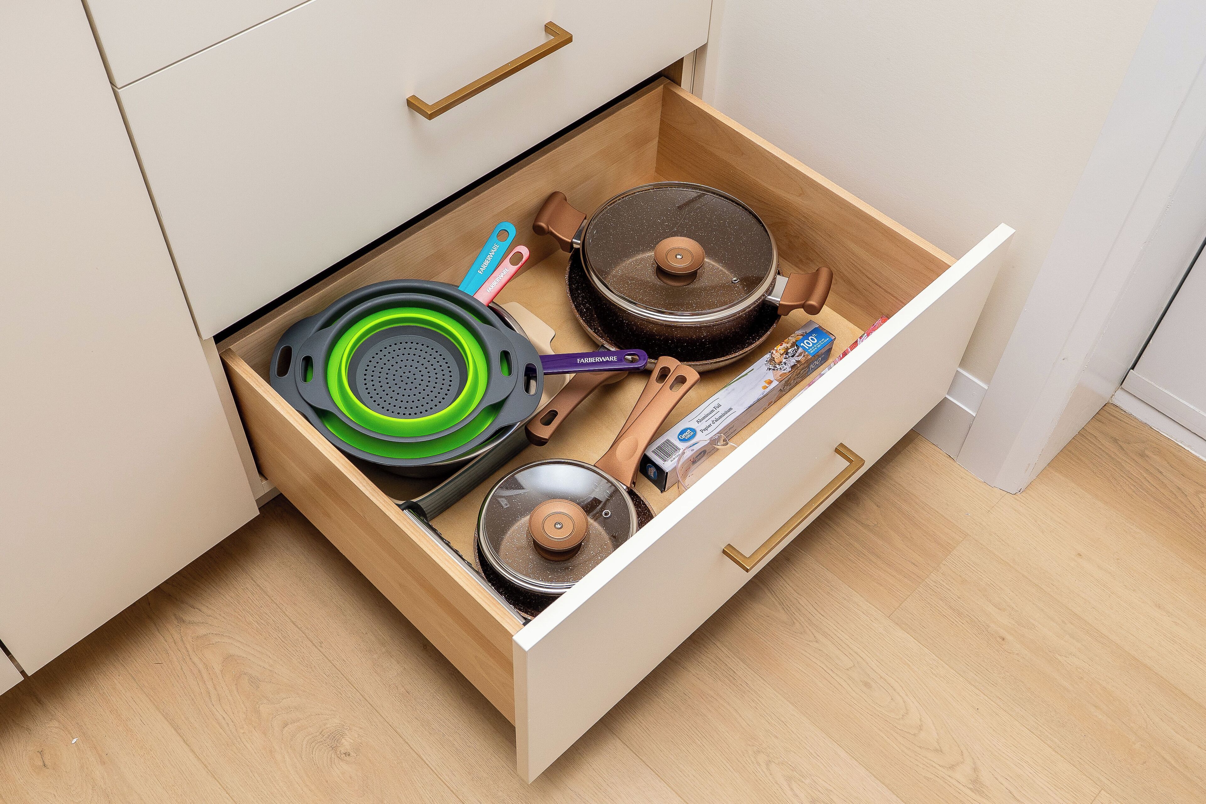 A kitchen drawer with various cookware items including pots, pans, and utensils.
