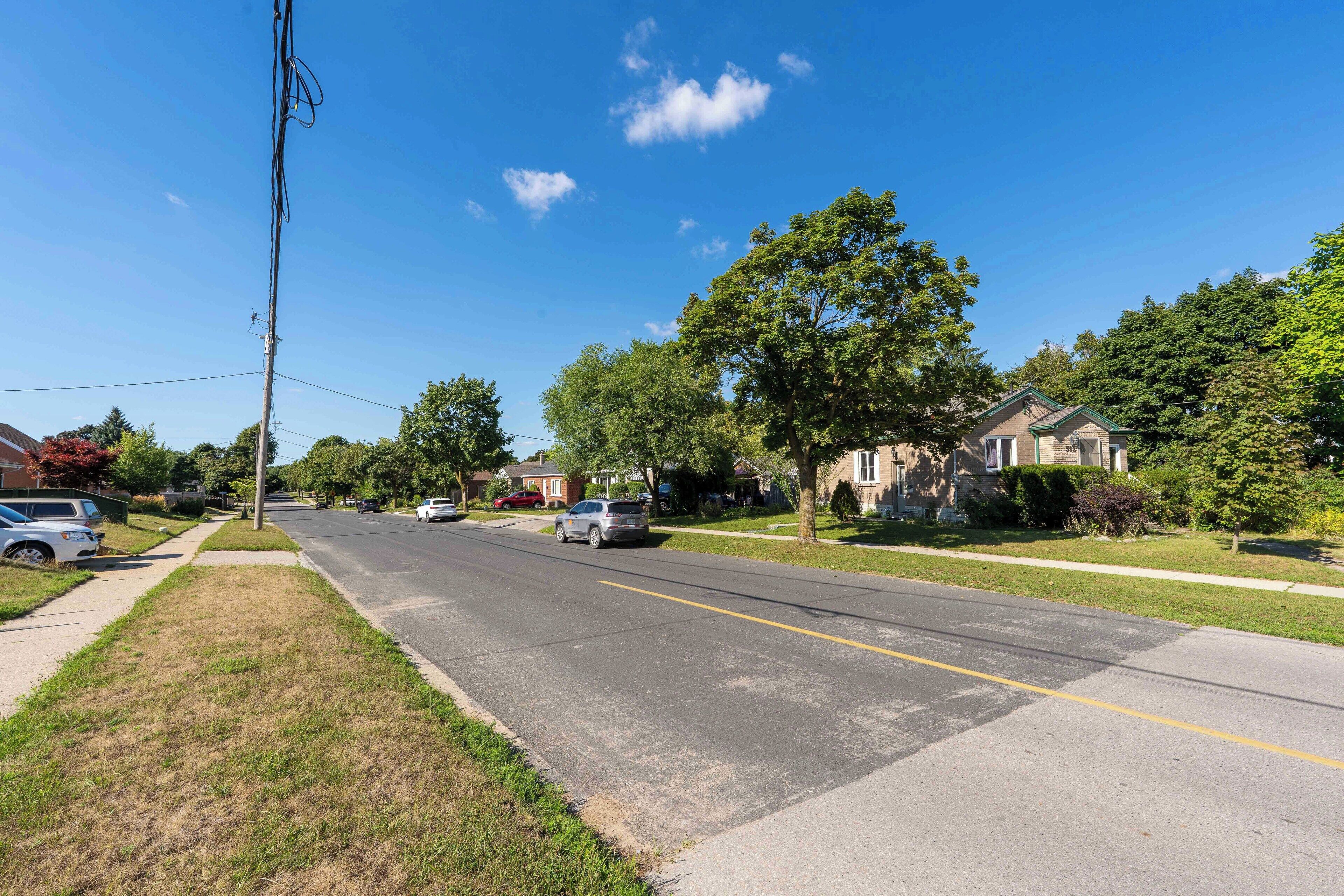A suburban street with houses, cars, and a clear blue sky.
