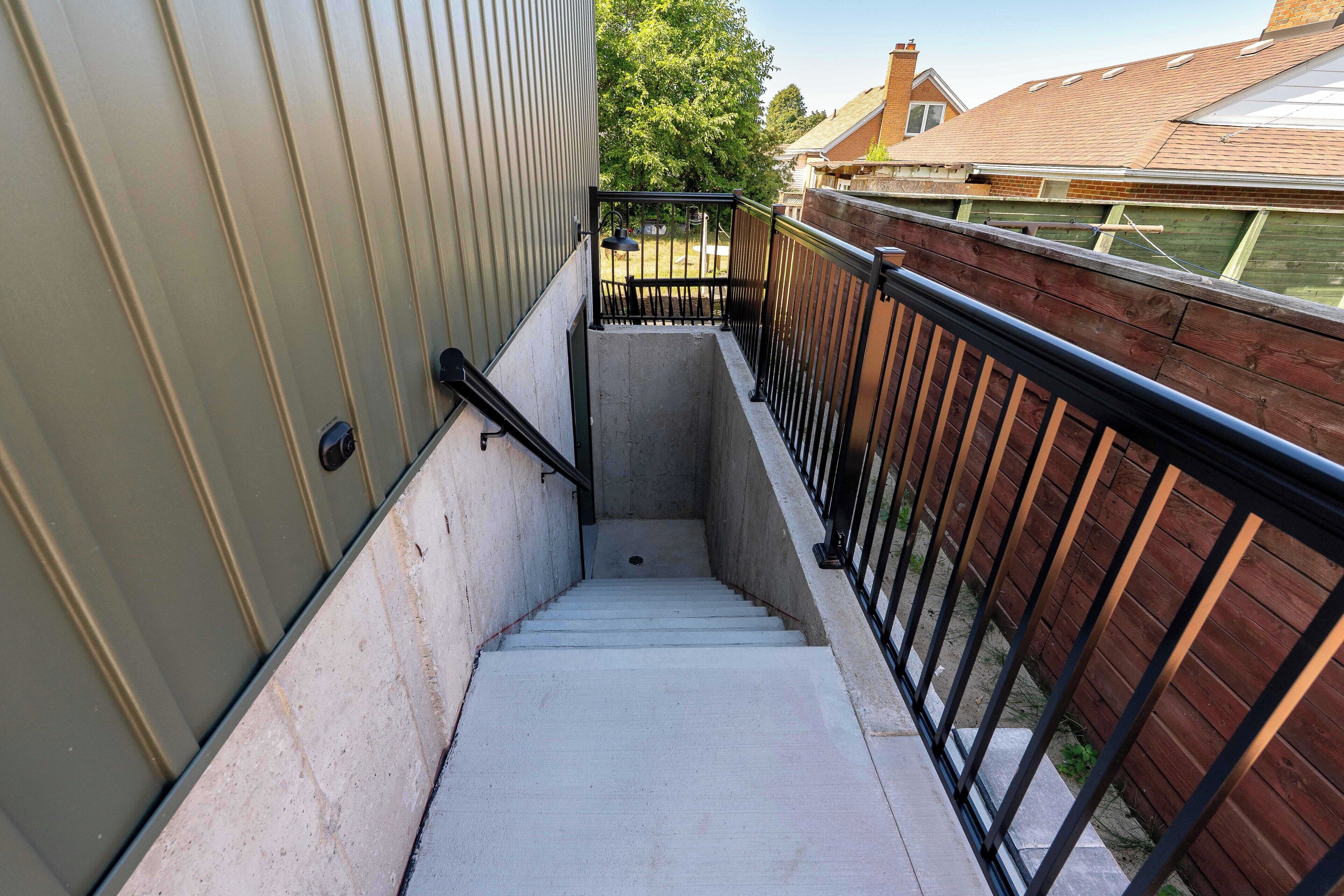 A concrete staircase with metal railings leading to a wooden deck.